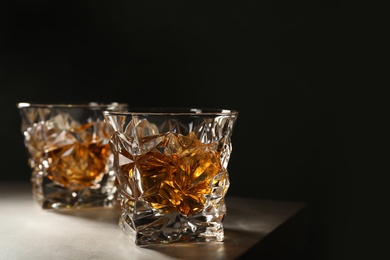 Golden whiskey in glass with ice cubes on table. Space for text