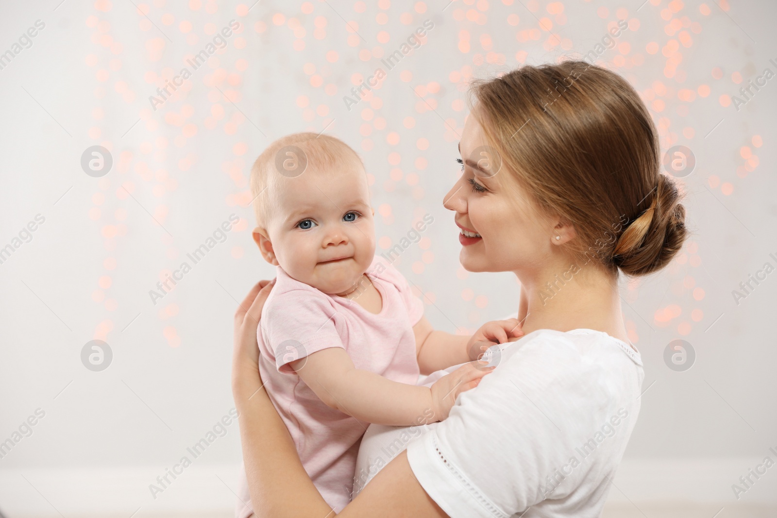 Photo of Portrait of happy mother with her baby against blurred lights