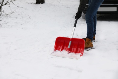 Photo of Man removing snow with shovel near car outdoors on winter day, closeup