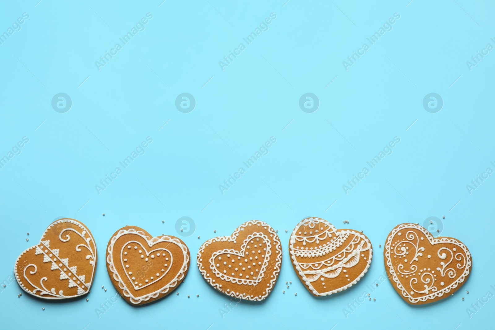 Photo of Tasty heart shaped gingerbread cookies on light blue background, flat lay. Space for text