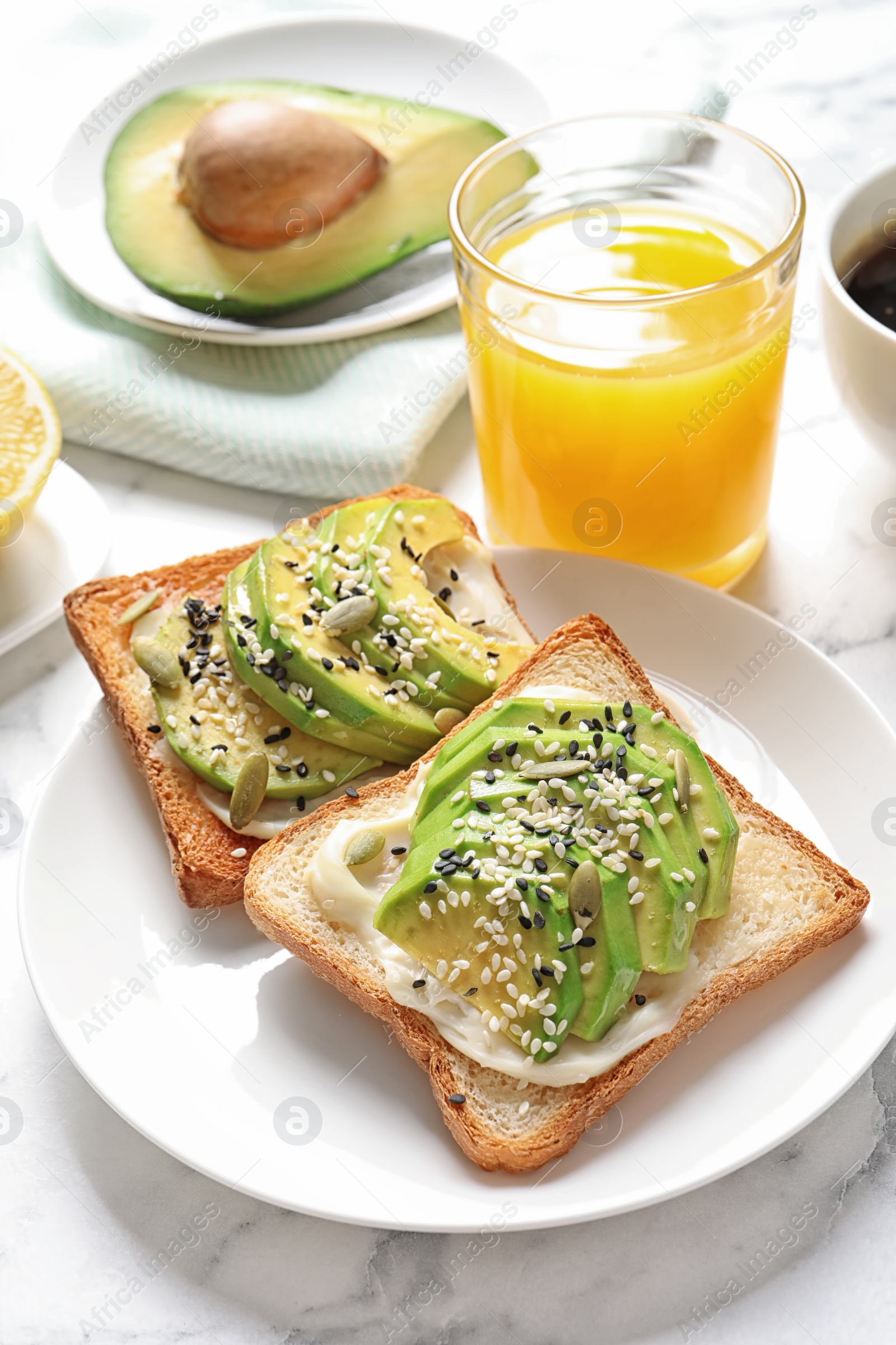 Photo of Toast bread with avocado and glass of juice on table