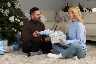 Photo of Happy couple exchanging Christmas gifts at home