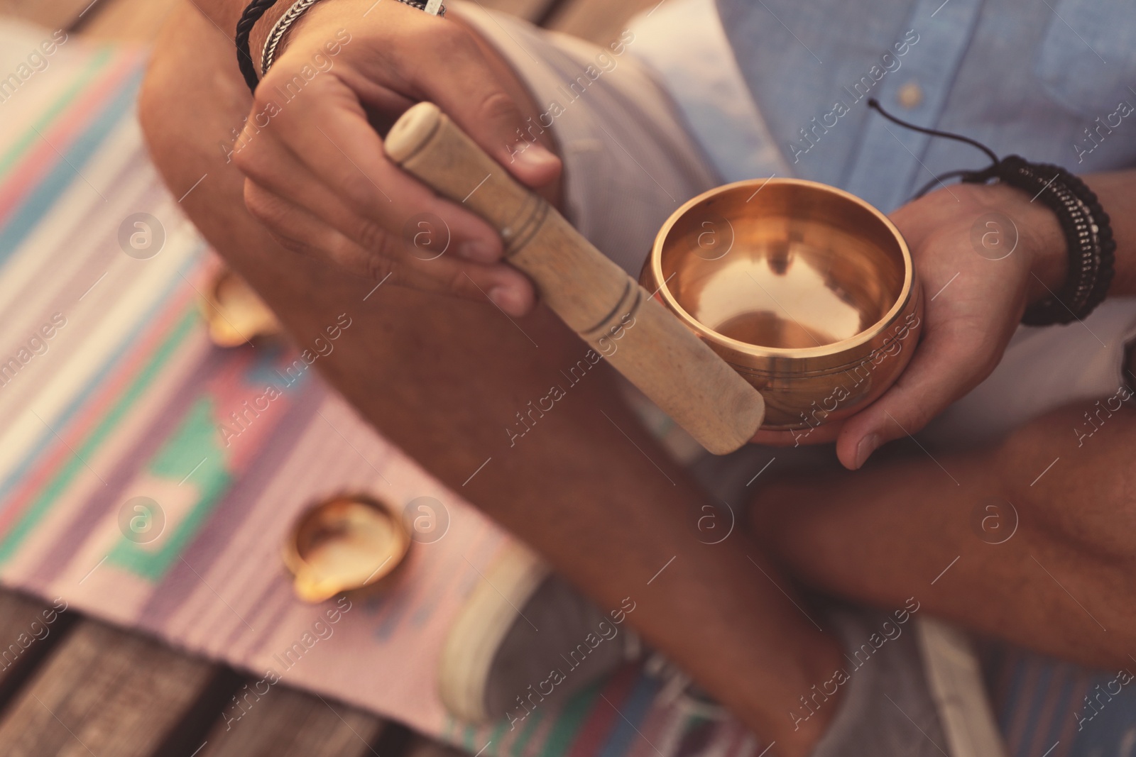 Photo of Man using Tibetan singing bowl outdoors, closeup