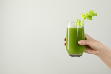 Woman holding glass of delicious celery juice on light grey background, closeup. Space for text