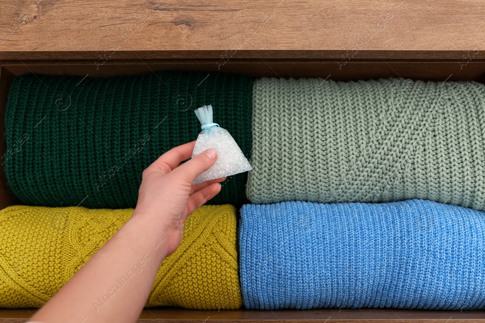 Photo of Woman putting scented sachet into drawer with clothes, closeup