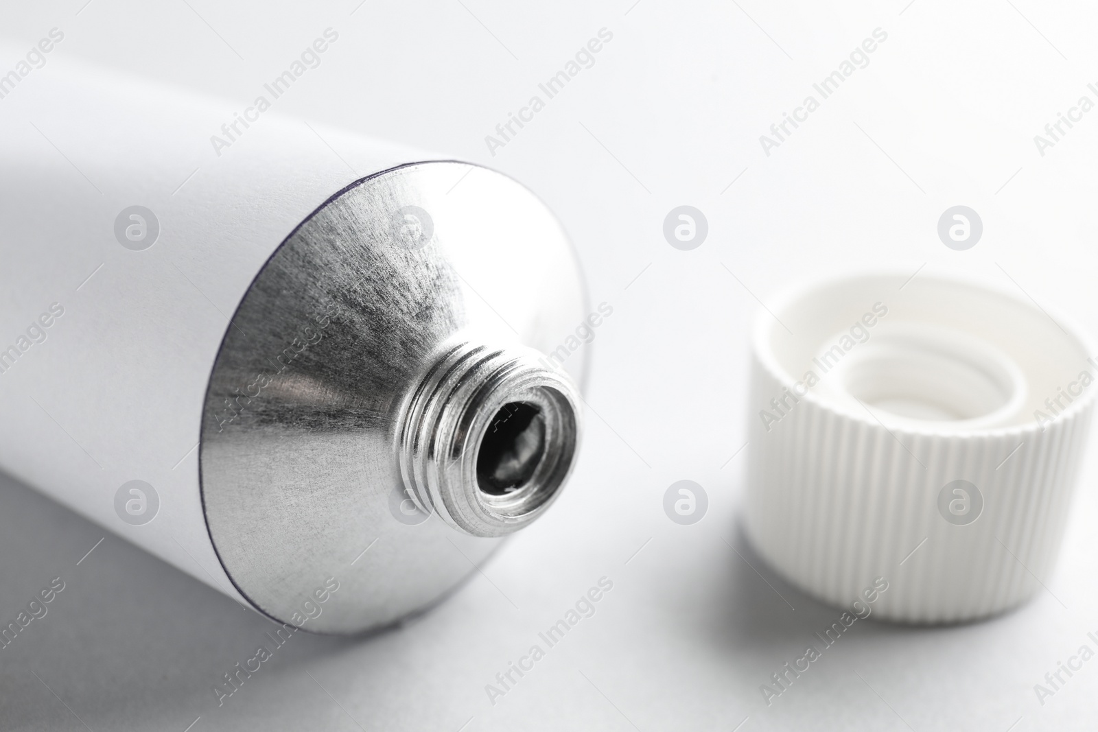 Photo of Open ointment tube on white background, closeup