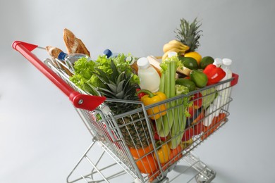 Shopping cart full of groceries on grey background