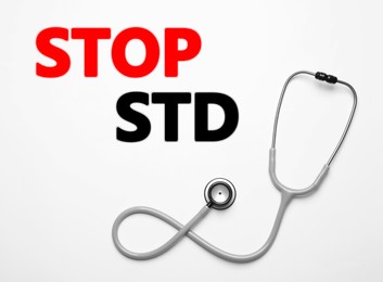 Text STOP STD and stethoscope on white background, top view 