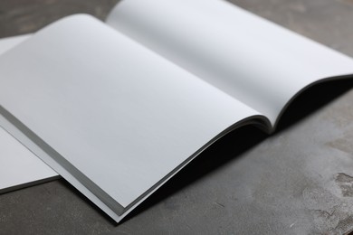 Photo of Open notebook with blank paper sheets on grey textured table, closeup. Mockup for design