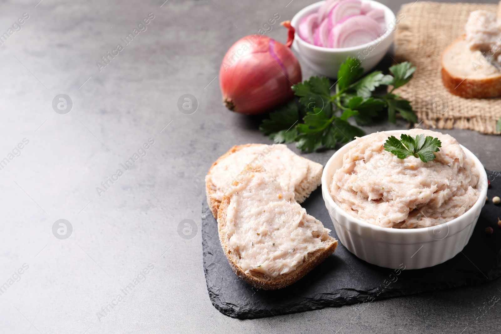 Photo of Delicious lard spread in bowl and sandwich on grey table. Space for text
