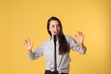 Photo of Young woman wearing casual clothes singing in microphone on color background