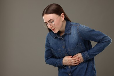Photo of Woman suffering from stomach pain on grey background, space for text