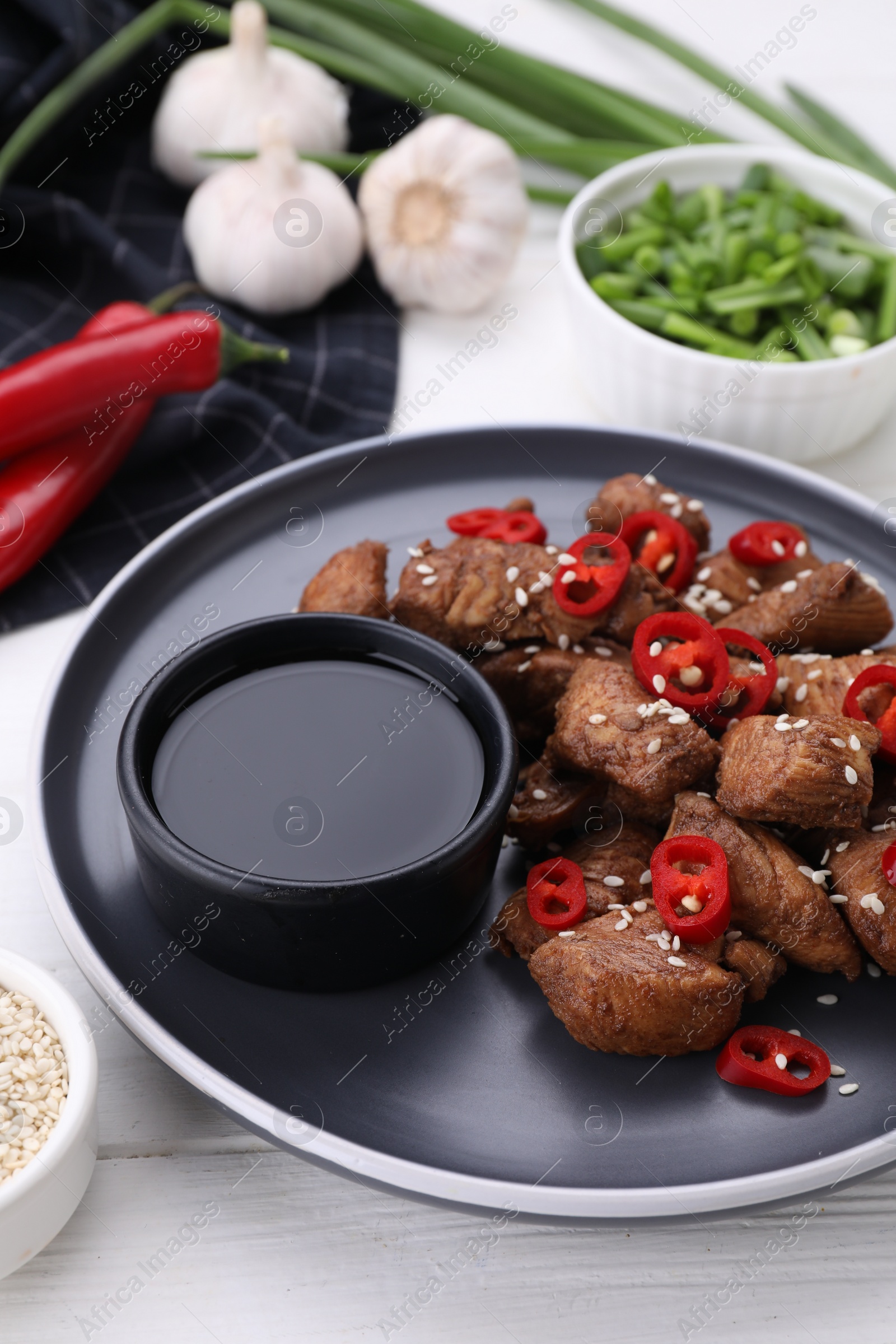 Photo of Plate with tasty soy sauce and roasted meat on white wooden table
