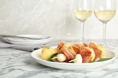 Photo of Melon, mozzarella and prosciutto skewers served on marble table. Space for text