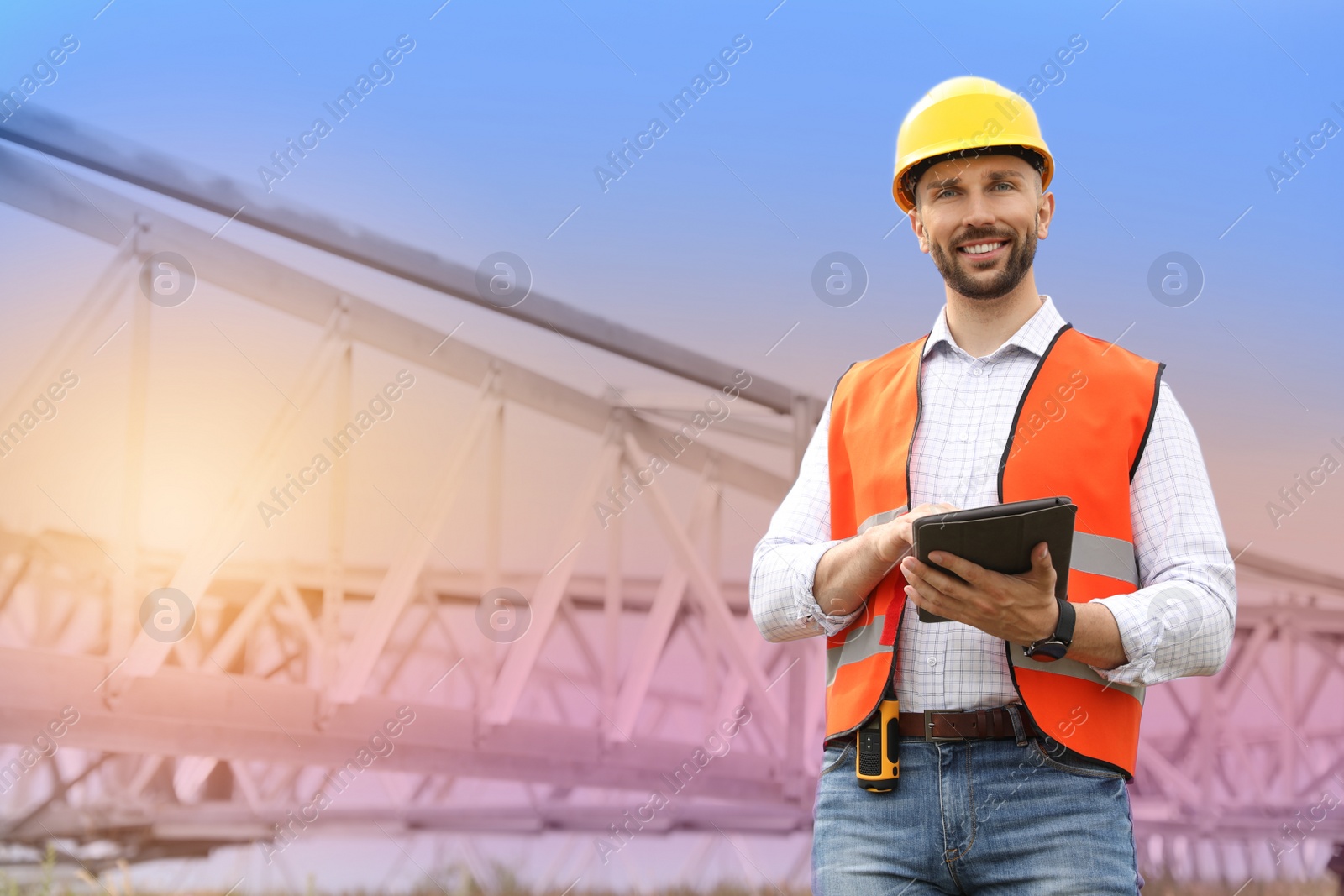 Photo of Professional engineer with tablet near high voltage tower construction outdoors. Installation of electrical substation