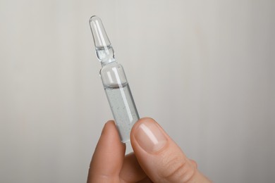 Photo of Woman holding pharmaceutical ampoule with medication on white background, closeup