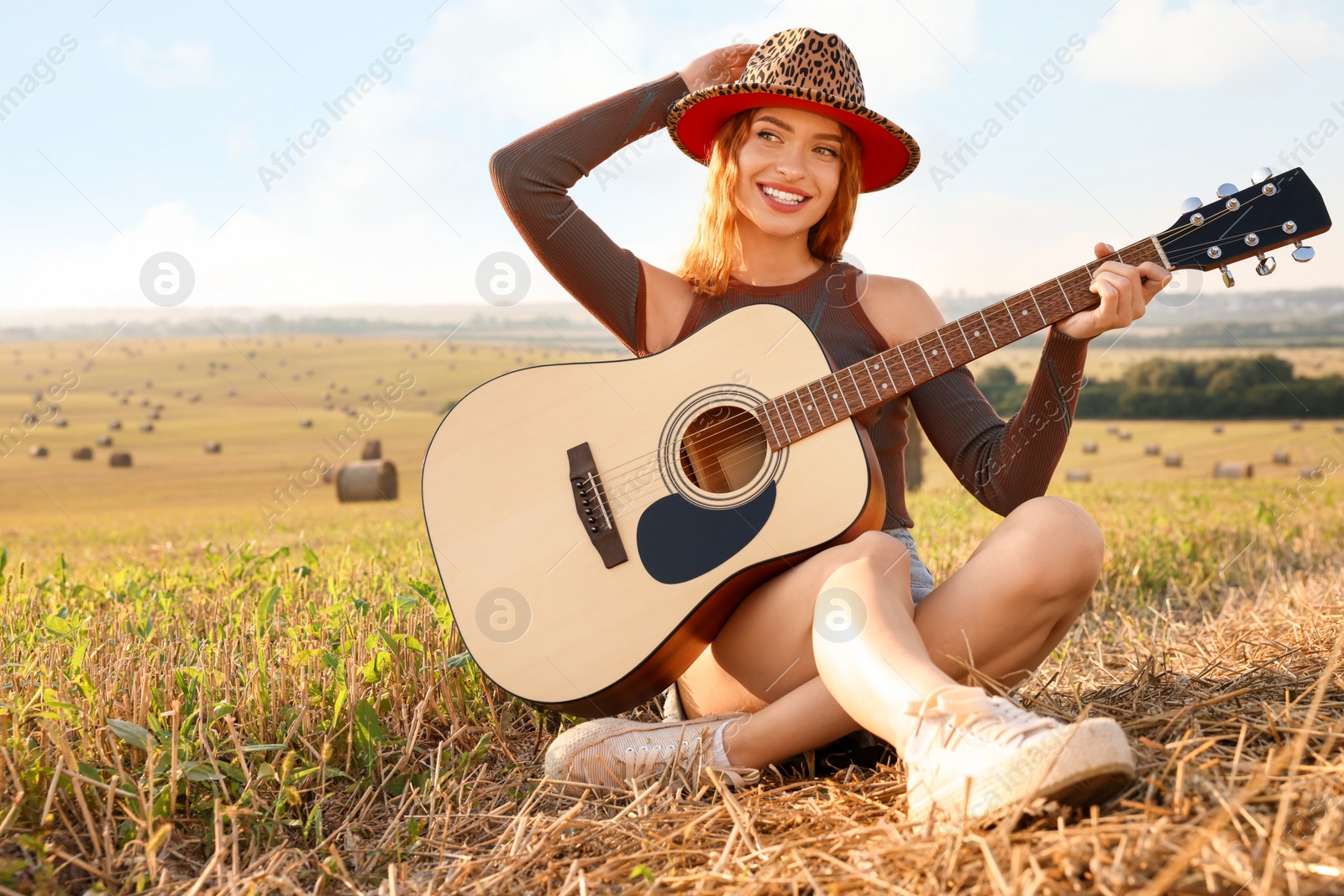 Photo of Beautiful happy hippie woman with guitar in field, space for text