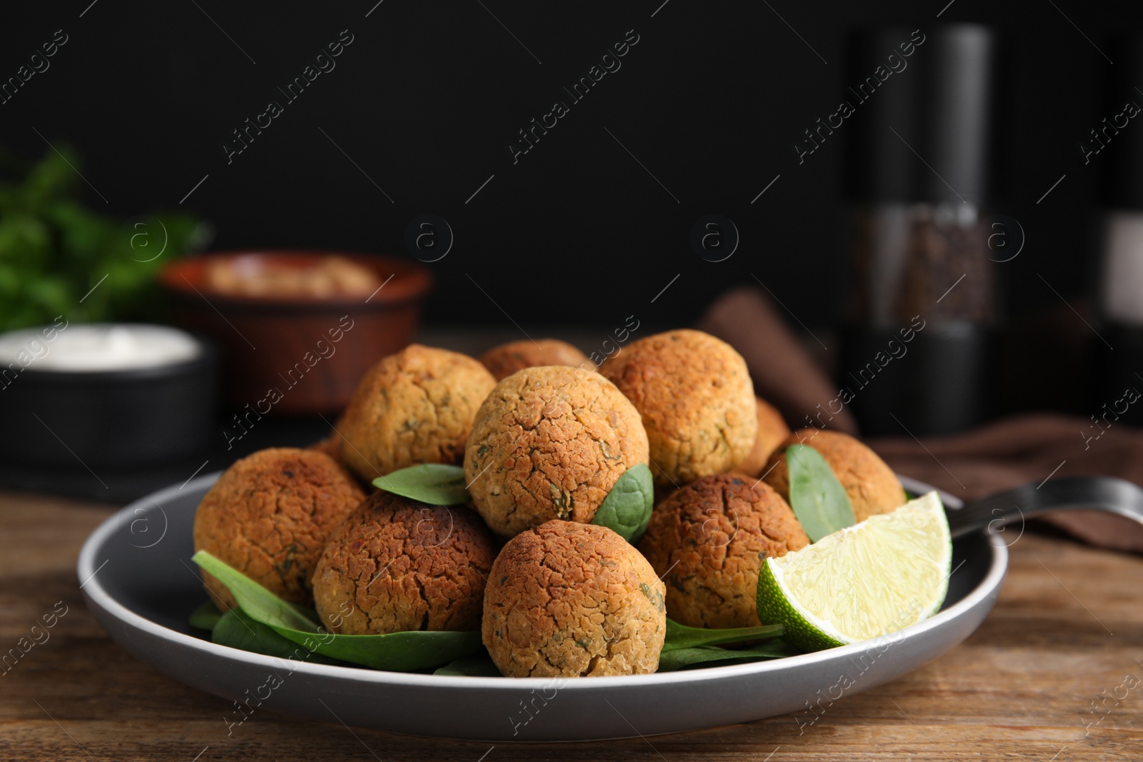 Photo of Delicious falafel balls with lime on wooden table, closeup