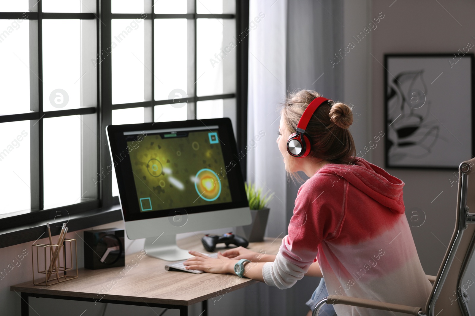 Photo of Young woman playing video game at home