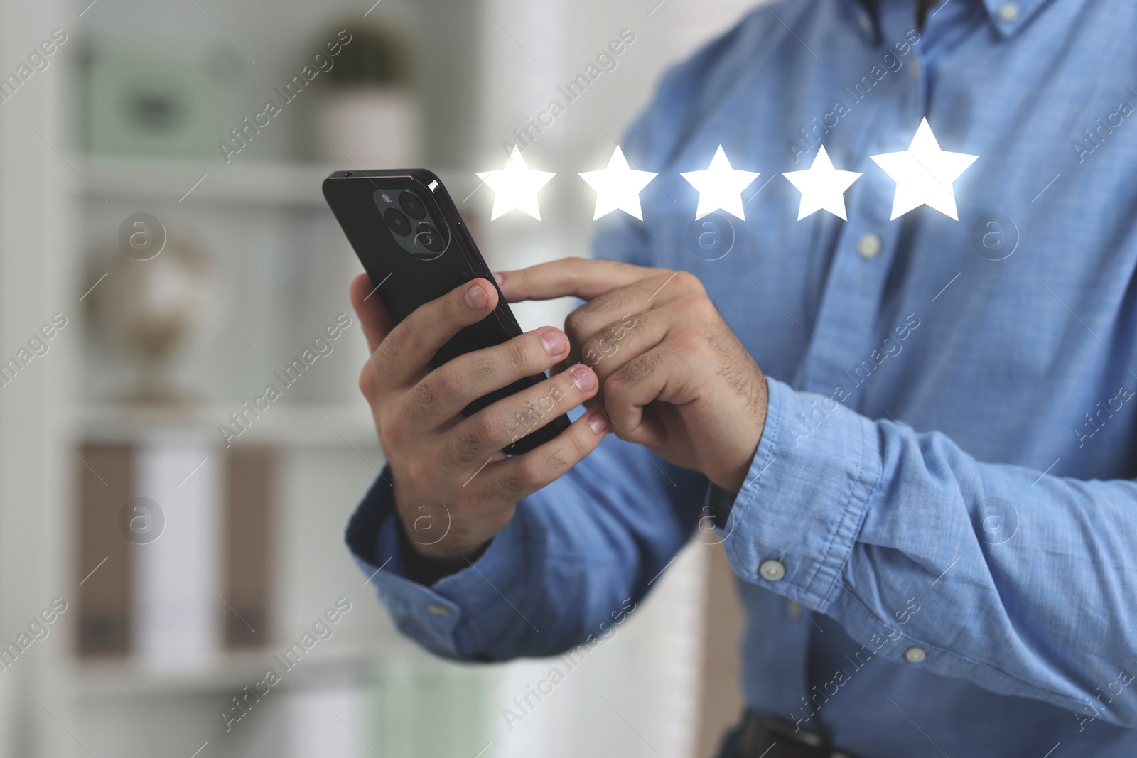 Image of Man leaving service feedback with smartphone at home, closeup. Stars over device