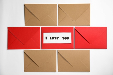 Card with phrase I Love You and envelopes on white background, flat lay