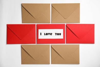 Photo of Card with phrase I Love You and envelopes on white background, flat lay