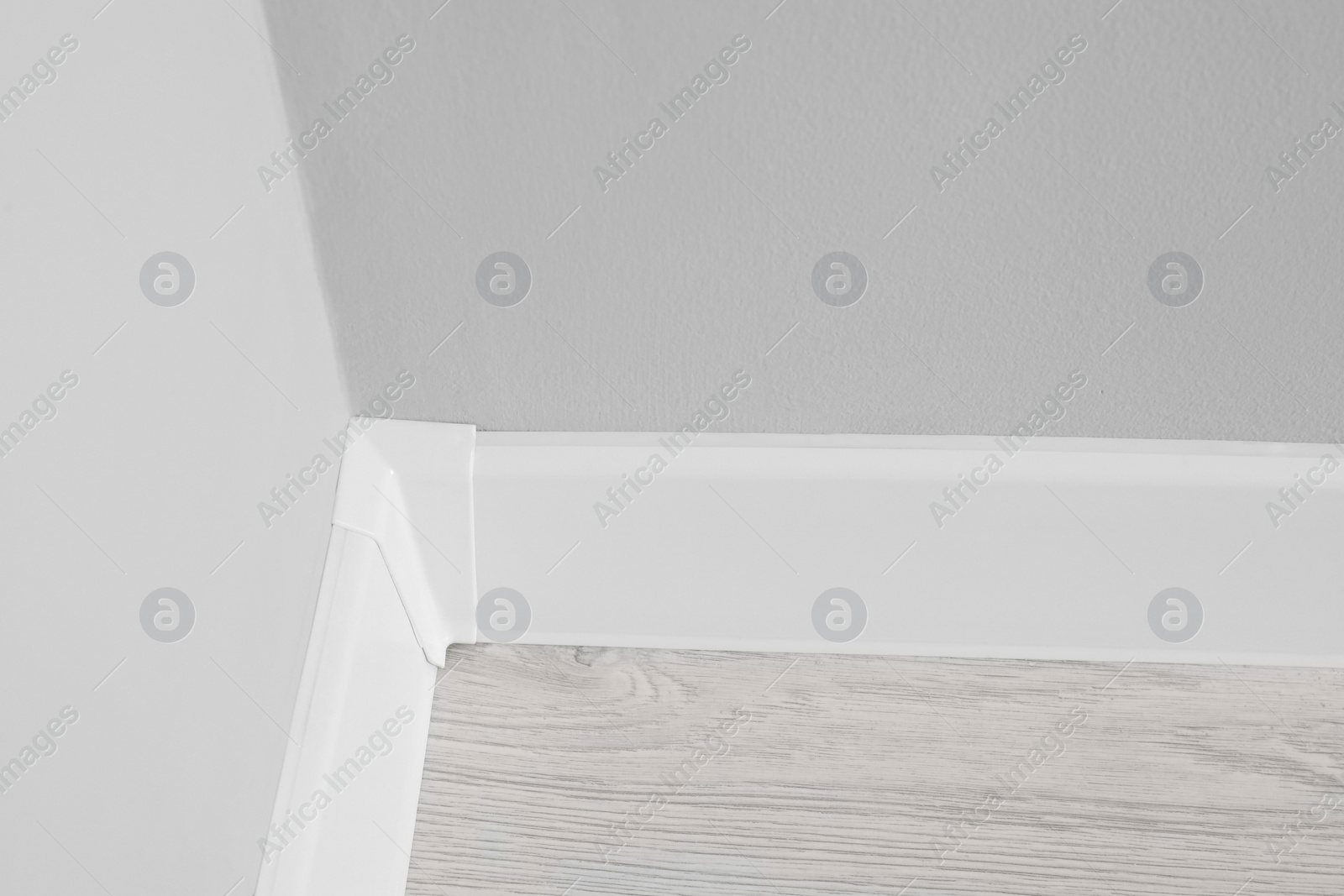 Photo of White plinth with connector on laminated floor near wall indoors, above view