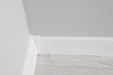White plinth with connector on laminated floor near wall indoors, above view