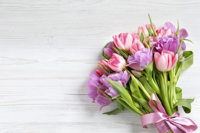 Photo of Beautiful bouquet of colorful tulip flowers on white wooden table, top view. Space for text