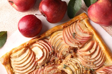 Photo of Tasty apple pie with nuts, fresh fruits and leaves on table, flat lay
