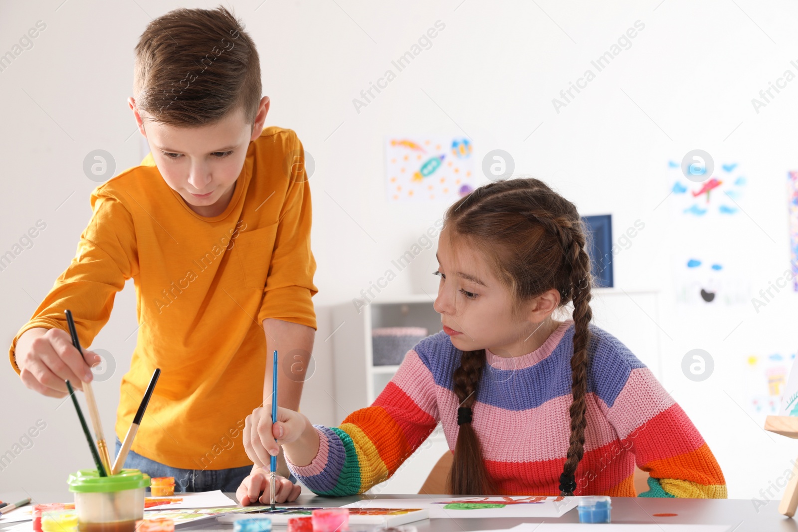 Photo of Little children painting picture at table indoors