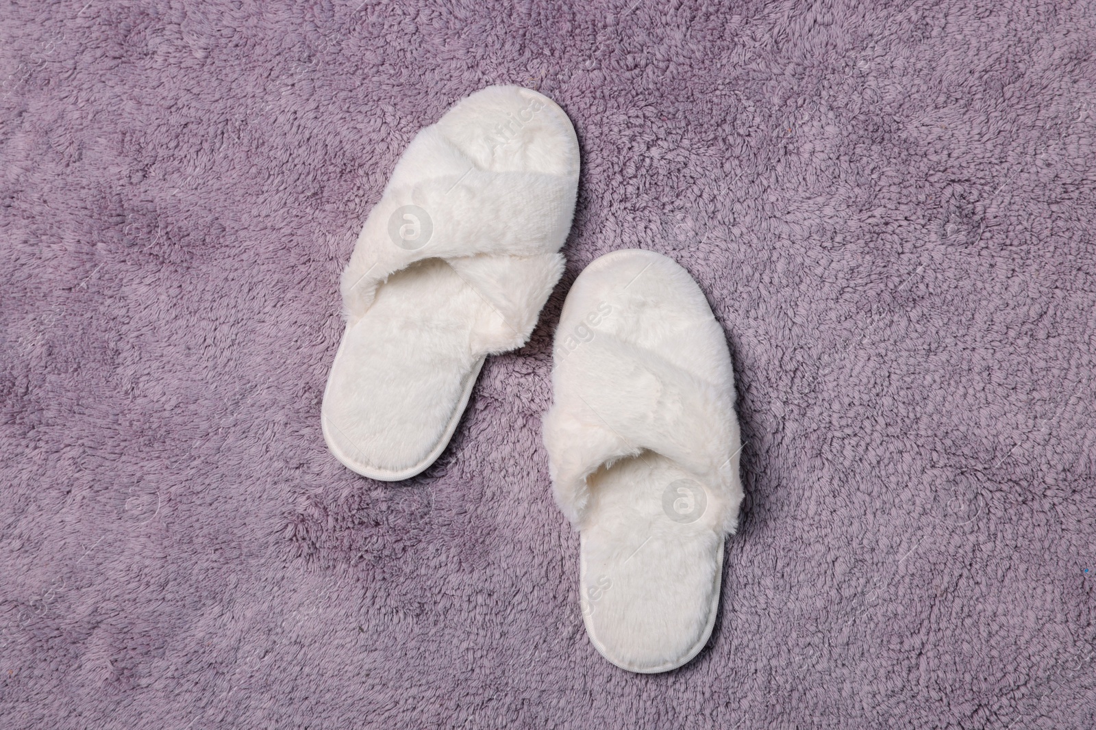 Photo of Soft white slippers on fluffy grey carpet, top view