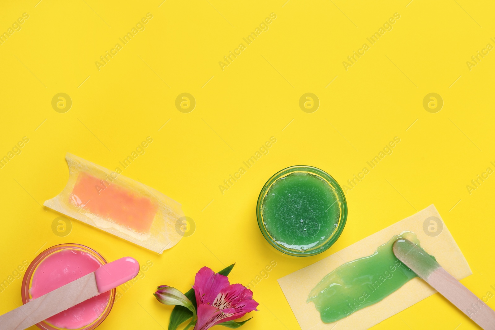 Photo of Flat lay composition with different types of wax and spatulas on yellow background. Space for text