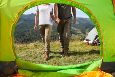Couple in mountains on sunny day, view from camping tent