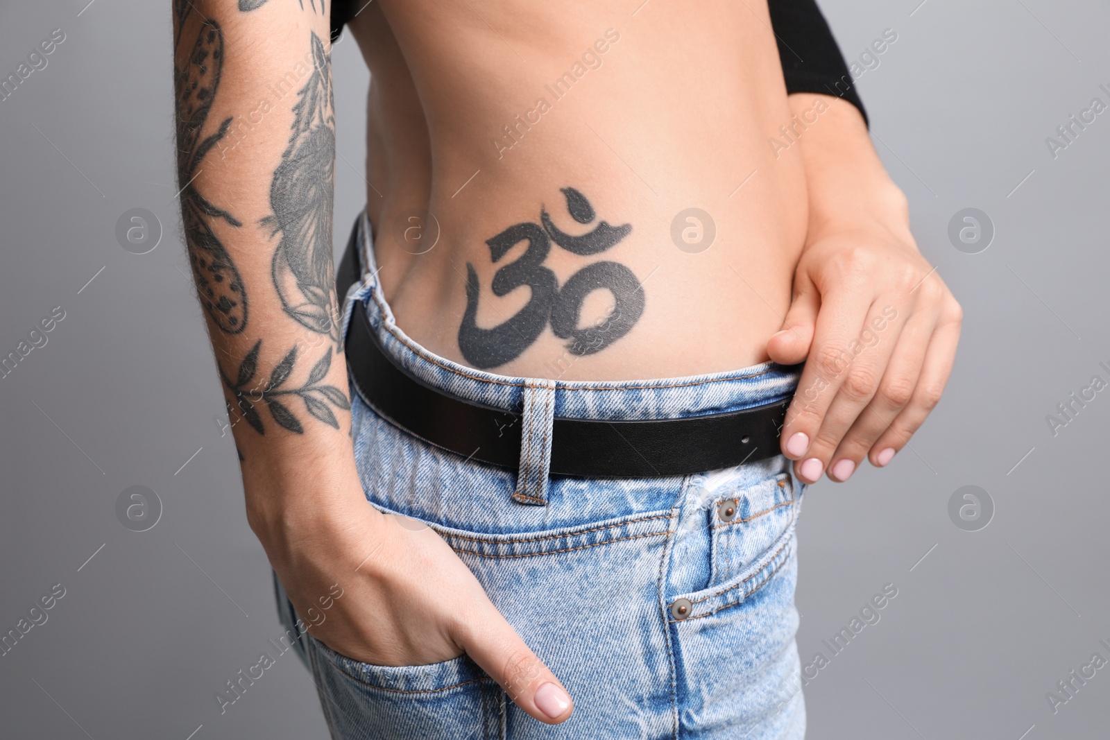 Photo of Beautiful woman with tattoos on body against grey background, closeup