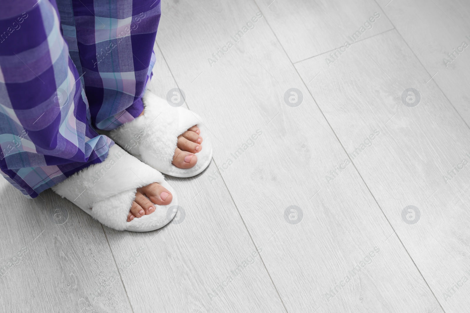 Photo of Woman wearing white soft slippers, closeup. Space for text