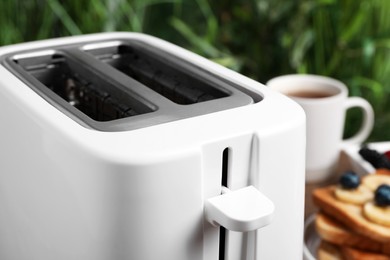 Modern white toaster and breakfast, closeup view