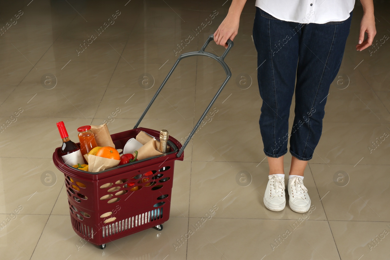 Photo of Woman with shopping basket full of different products, closeup