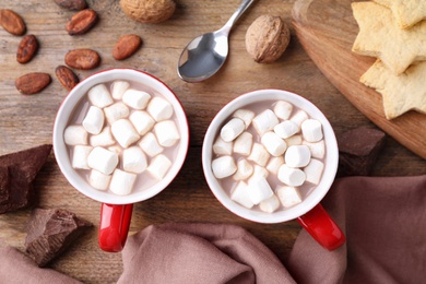 Photo of Flat lay composition of tasty cocoa with marshmallows on wooden table