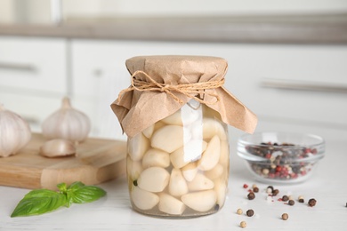 Composition with jar of pickled garlic on wooden table indoors