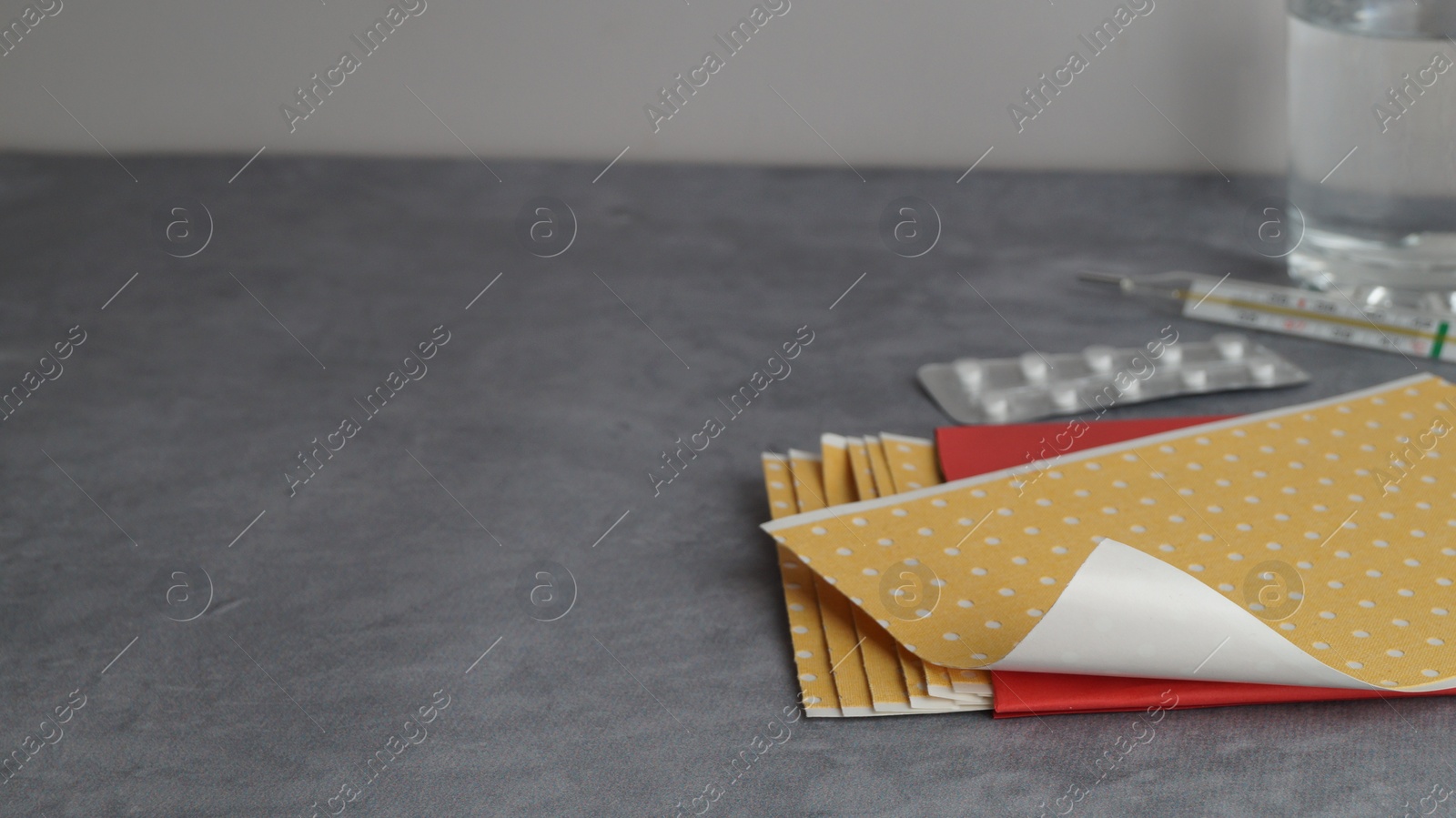 Photo of Pepper plasters and pills on grey textured background, closeup. Space for text