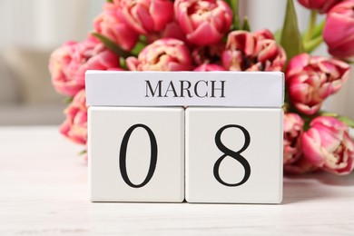 Photo of International Women's day - 8th of March. Block calendar and bouquet of beautiful tulips on white wooden table, closeup