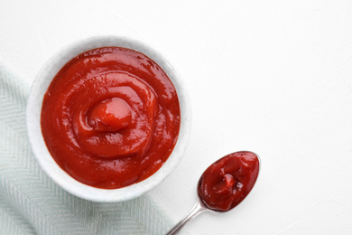 Photo of Tasty tomato sauce and spoon on white table, flat lay. Space for text