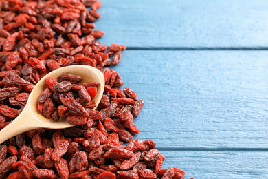 Photo of Dried goji berries on blue wooden table, top view. Space for text