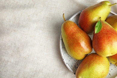 Photo of Plate with ripe juicy pears on light fabric. Space for text