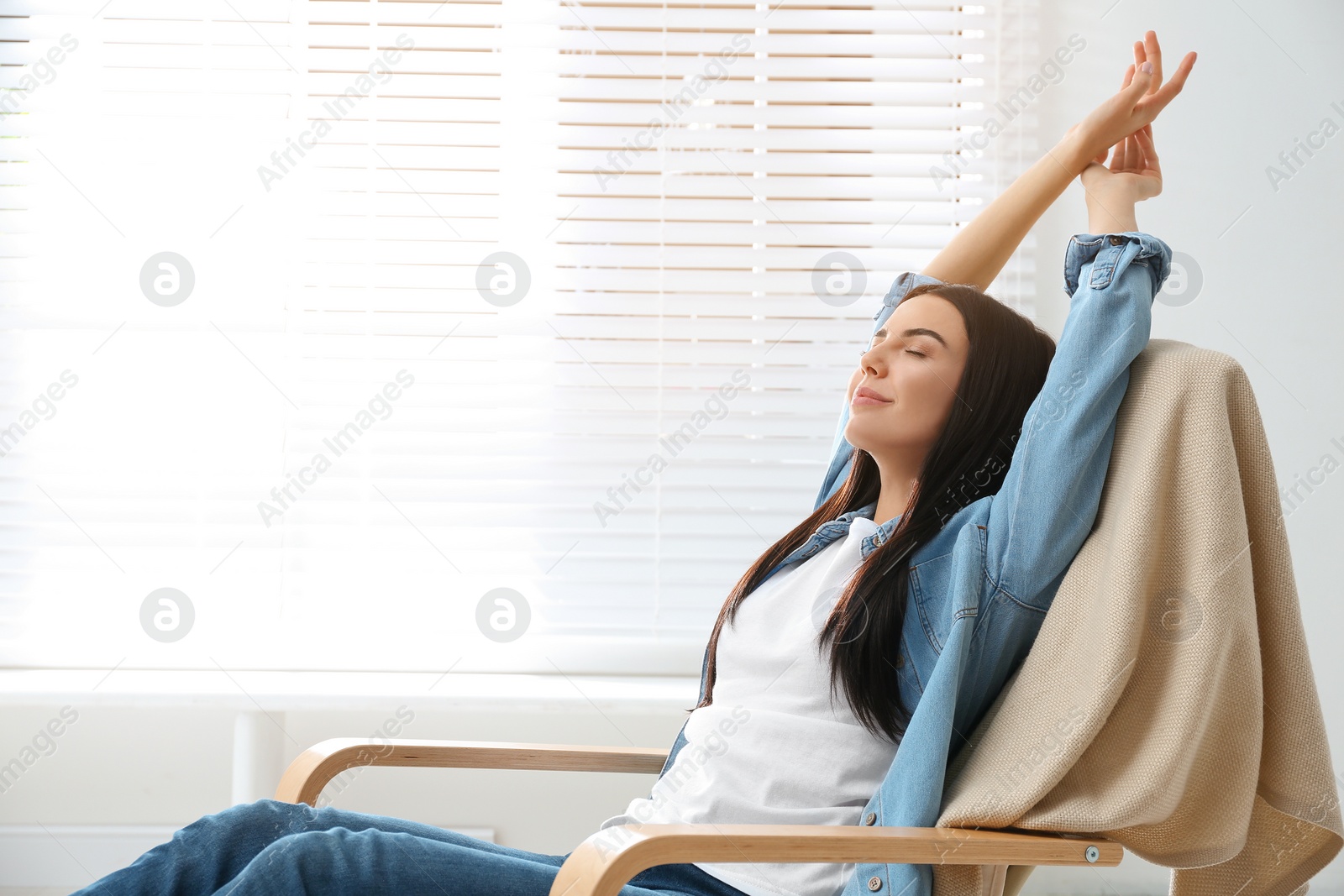 Photo of Young woman relaxing in armchair near window at home