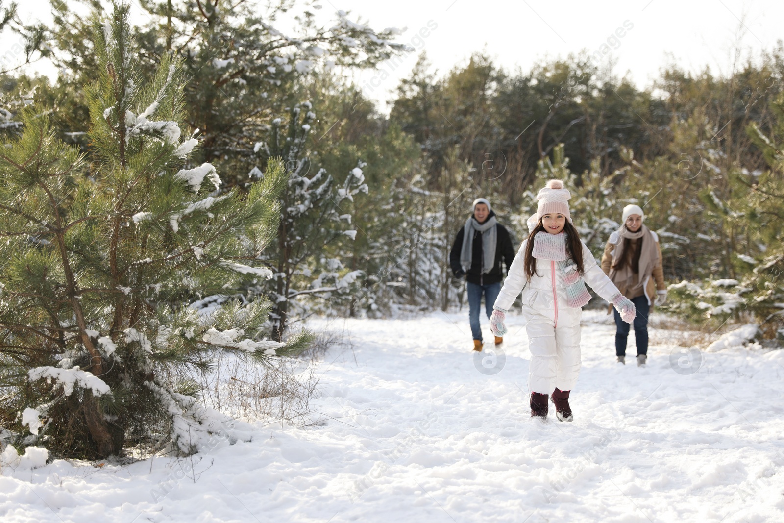 Photo of Cute little girl with her parents outdoors on winter day. Christmas vacation