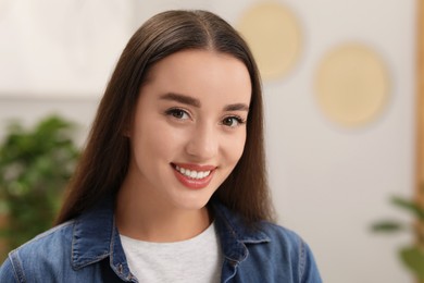 Portrait of beautiful young woman indoors. Attractive lady smiling and looking into camera