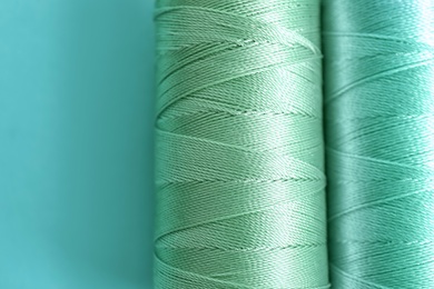 Photo of Mint color sewing threads on table, closeup