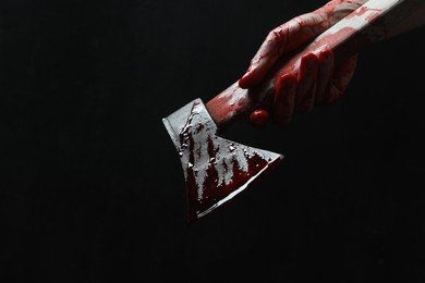 Photo of Man holding bloody axe on black background, closeup